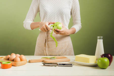 House wife wearing apron making. Steps of making cooking apple cake. Cutting green apple.の写真素材