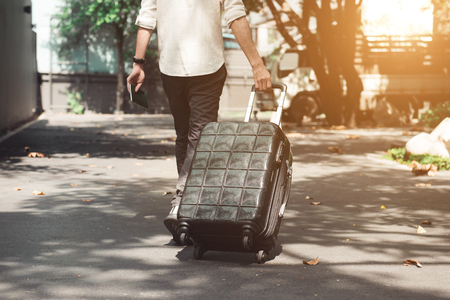 Young man and traveling luggage suitcase walkingの写真素材