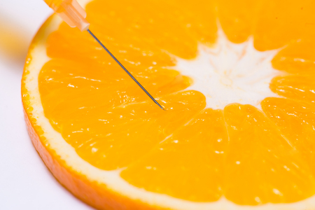 Science experiment with orange and syringe isolated on white.の写真素材