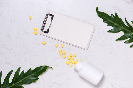 Yellow pills and blank notebook on table. Flat lay.の写真素材