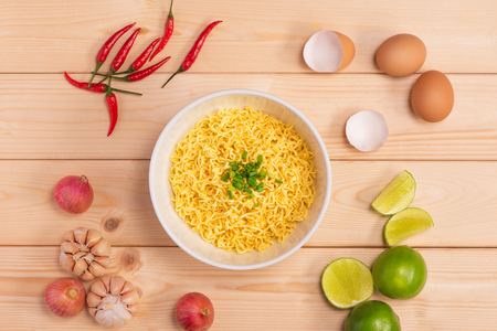Instant noodles in bowl with vegetables on wood backgroundの写真素材