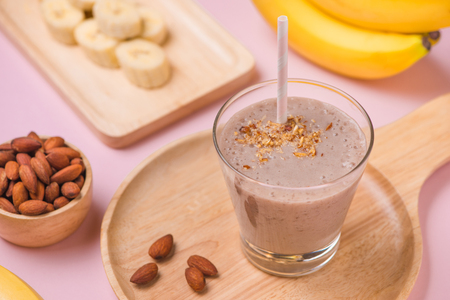 Fresh made banana smoothie in a glass on pink backgroundの写真素材