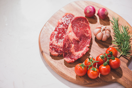 Raw beef on a cutting board  with spices and ingredients for cooking.の写真素材