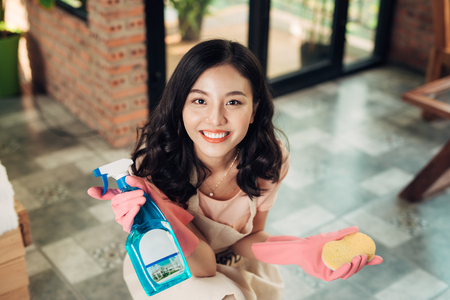Cheerful asian woman holding spray bottle, ready to cleaning window.の写真素材