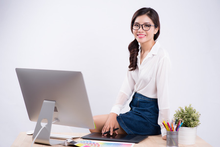 Beautiful graphic designer using graphics tablet to do her work at deskの写真素材