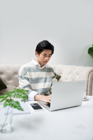 Young asian student using laptop at the city cafe shop.の写真素材