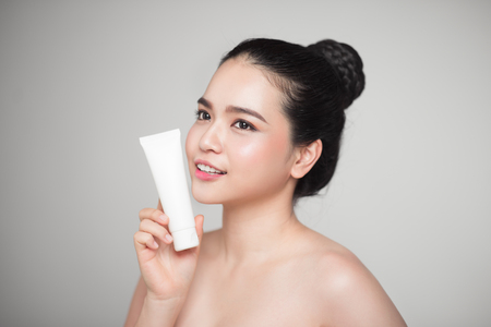Beauty concept. Asian pretty woman with perfect skin holding cosmetic bottleの写真素材