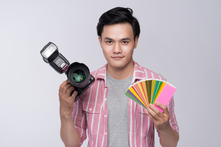 Young asian photographer holding digital camera, while working in studioの写真素材