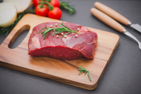 Raw beef on a cutting board  with spices and ingredients for cooking.の写真素材