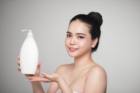 Shampoo. Joyful young woman advertising care product.の写真素材