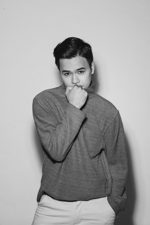 Young asian man's portrait against black backgroundの写真素材