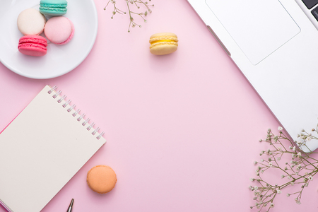 Flatlay of laptop, cake macaron and cup of tea on pink table. Beautiful breakfast with macaroon.の写真素材