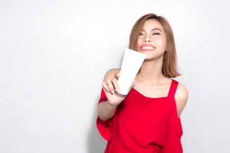 Beautiful asian woman standing red dress and holding cosmetic product.の写真素材