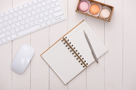 White desk with colorful macaroons, keyboard and open notebook.の写真素材