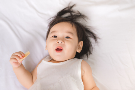 Cute little girl eating cookie at homeの写真素材