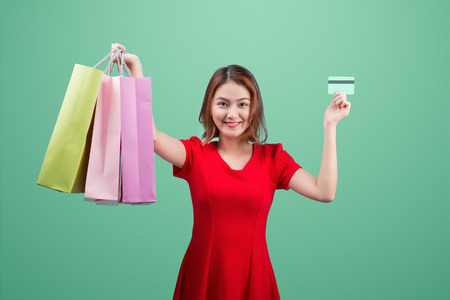 Santa asian woman holding shopping bags and credit card against blue vignetteの写真素材