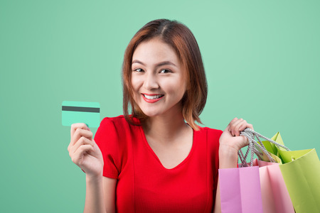 Santa asian woman holding shopping bags and credit card against blue vignetteの写真素材