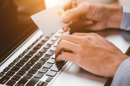 Hands holding plastic credit card and using laptop. Online shopping concept. Retro color.の写真素材