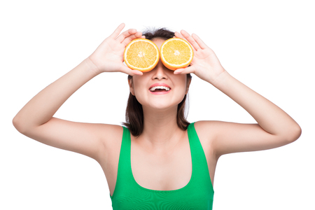 Tropical fruits. Healthy eating. Charming young asian woman holding fresh oranges and smiles.の写真素材