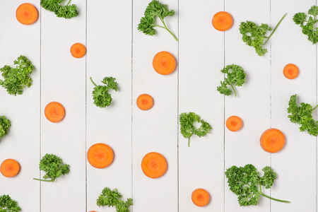 Fresh raw peeled carrot slices with vegetables on wooden table.の写真素材