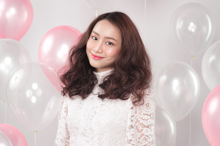 Asian pretty fashionable woman in white dress with pastel balloonsの写真素材