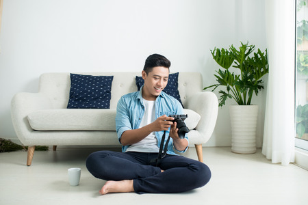 Asian man sitting on the floor and looking at camera near the window at home.の写真素材