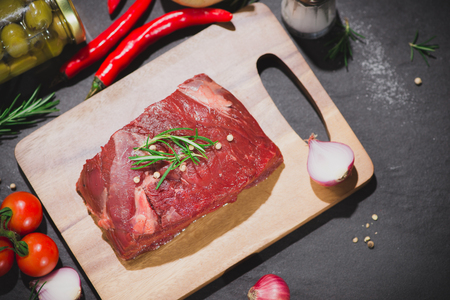 Raw beef on a cutting board  with spices and ingredients for cooking.の写真素材