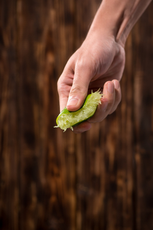 Hand squeeze lime with lime drop on dark wooden backgroundの写真素材