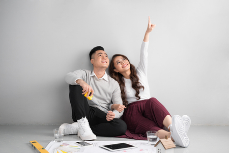 Young asian adult couple sitting on flor planning new home design.の写真素材