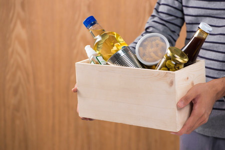 Volunteer with donation box with foodstuffs on wooden backgroundの写真素材