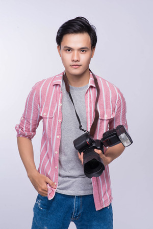 Young asian photographer holding digital camera, while working in studioの写真素材