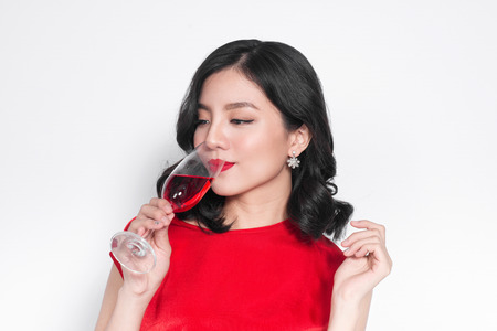 Young celebrating asian woman in red dress holding wine glass.の写真素材