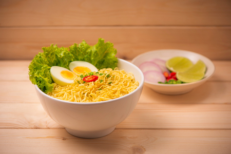 Instant noodles in bowl with vegetables and  boiled egg on wood backgroundの写真素材