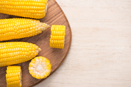 Sweet corn on cobs on cutting board on wooden table.の写真素材