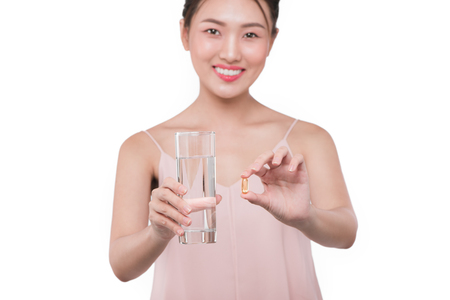 Smiling asian woman  eating pills and drinking waterの写真素材