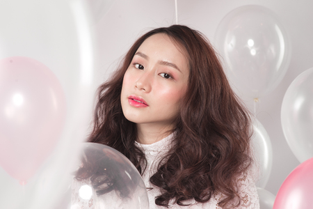 Asian pretty fashionable woman in white dress with pastel balloonsの写真素材