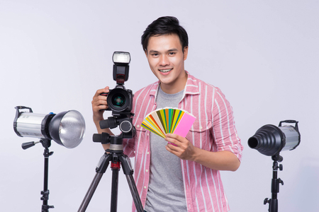 Young asian photographer holding digital camera, while working in studioの写真素材