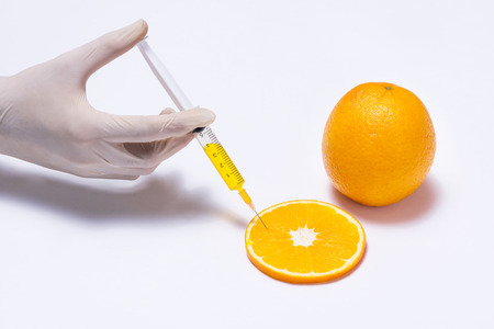 Science experiment with orange and syringe isolated on white.の写真素材