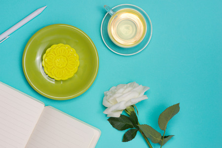 Snow skin mooncake and tea cup with flowers on dark background. Open notebook with copy-space.の写真素材