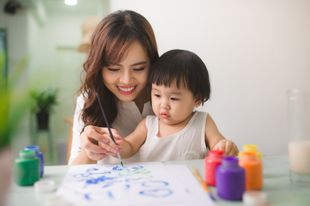 Happy family mother and daughter together paint. Asian woman helps her child girl.の写真素材