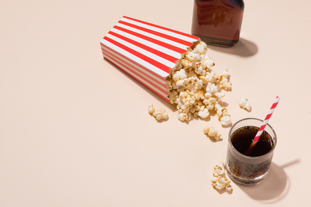 Popcorn in red and white cardboard with glass of sodaの写真素材