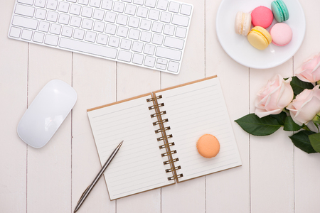 White desk with colorful macaroons, keyboard and open notebook.の写真素材