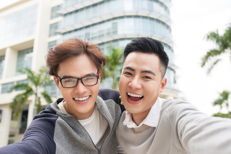 Two Vietnamese men traveler taking selfie in foreign cityの写真素材