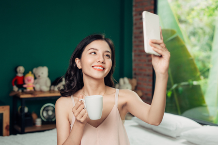 Health asian woman smile take a selfie and she sitting on the bed at homeの写真素材