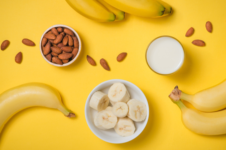 Fresh banana and almonds with milk on yellow background.の写真素材