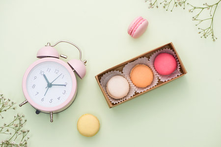 French macaroons. Many variegated sweet macarons in box with bouquet of pink roses on the tableの写真素材