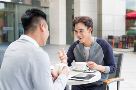 Two asian man sitting in cafe and discussingの写真素材