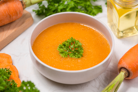 Carrot soup with cream and parsley on white stone background. Top view. Copy spaceの写真素材