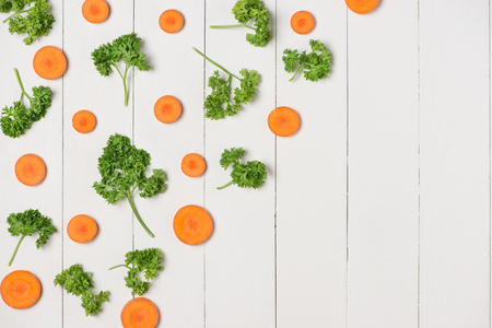 Fresh raw peeled carrot slices with vegetables on wooden table.の写真素材