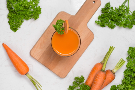 Glass of fresh carrot juice with vegetables on table.の写真素材